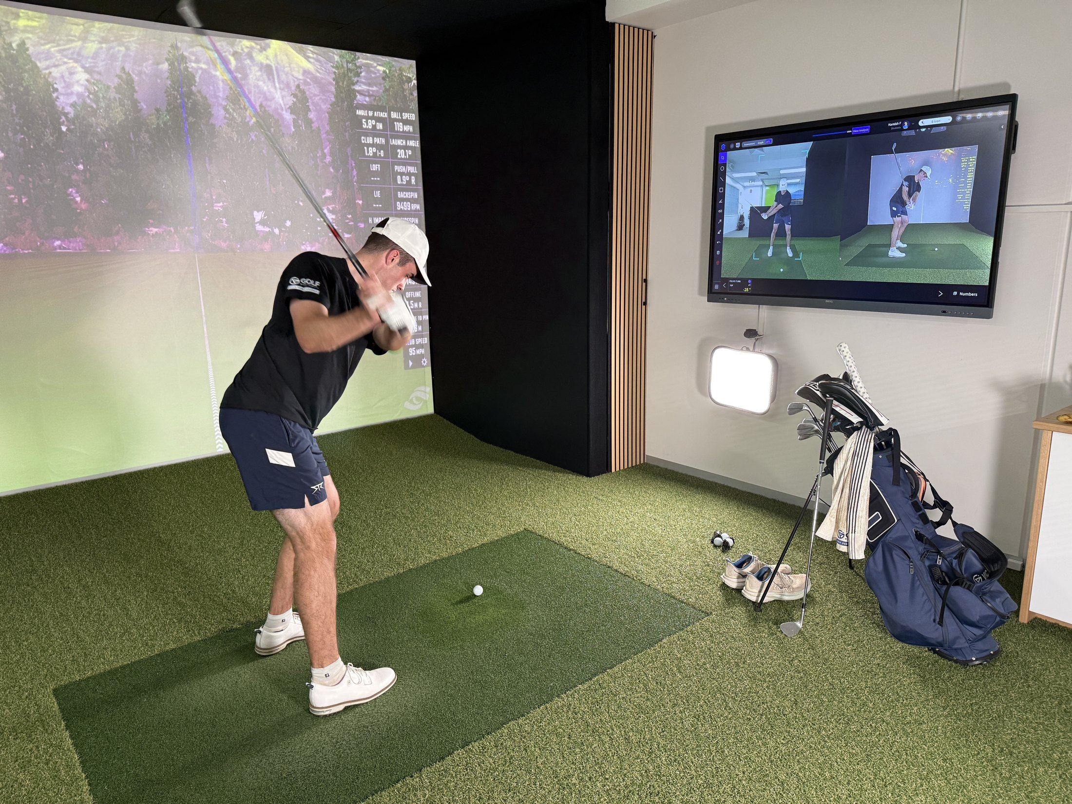 Hamish hitting a golf shot in a simulator beside swing-analysis feedback